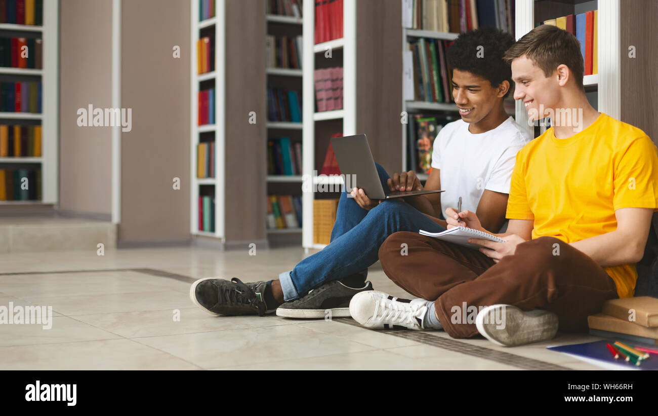 Two young guys studying on floor in library Stock Photo