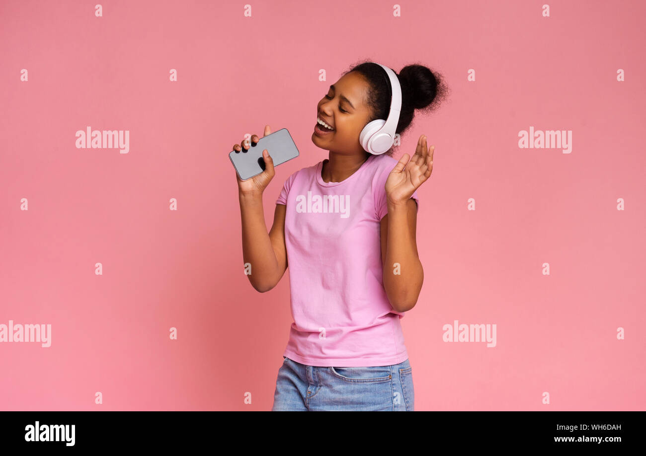 Happy african american teen singing into smartphone like microphone Stock Photo