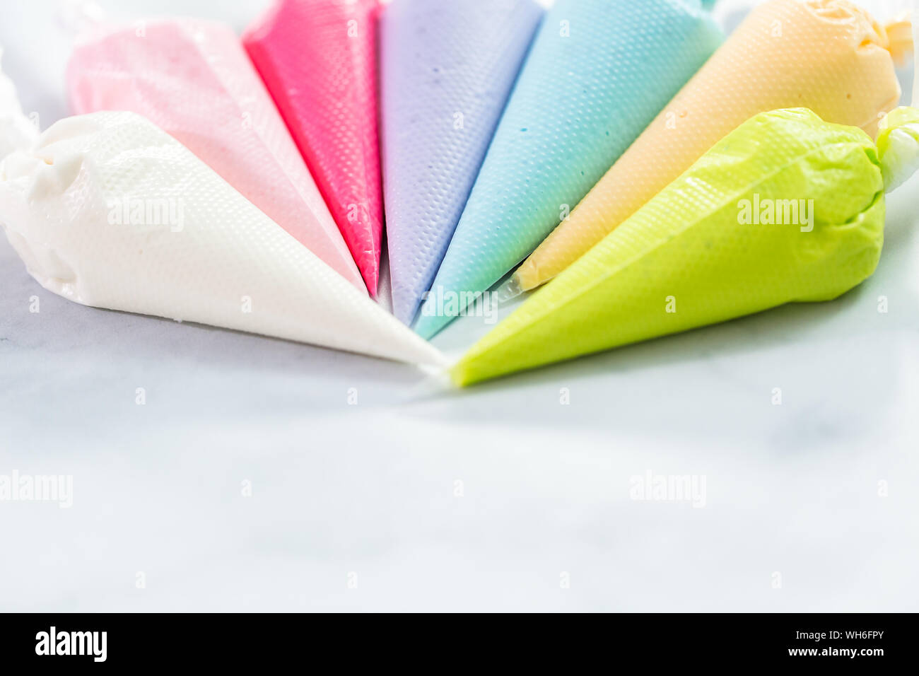 Piping bags with pastel color royal icing to decorate Easter sugar