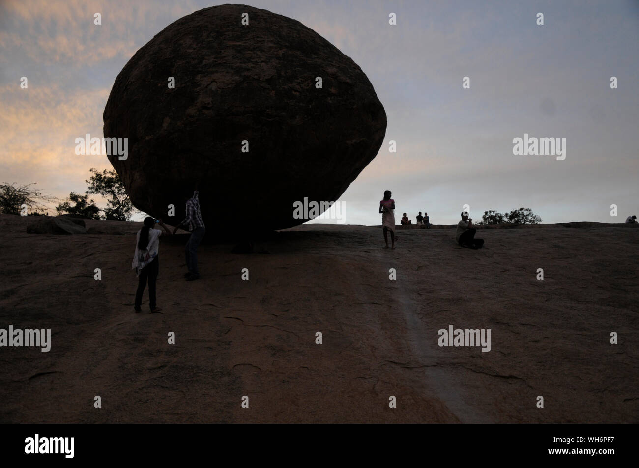 Tourists on a steep rock slope in the historic town of Mahabalipuram Tamil Nadu India where the massive round boulder known as “Krishna’s Butter Ball” Stock Photo