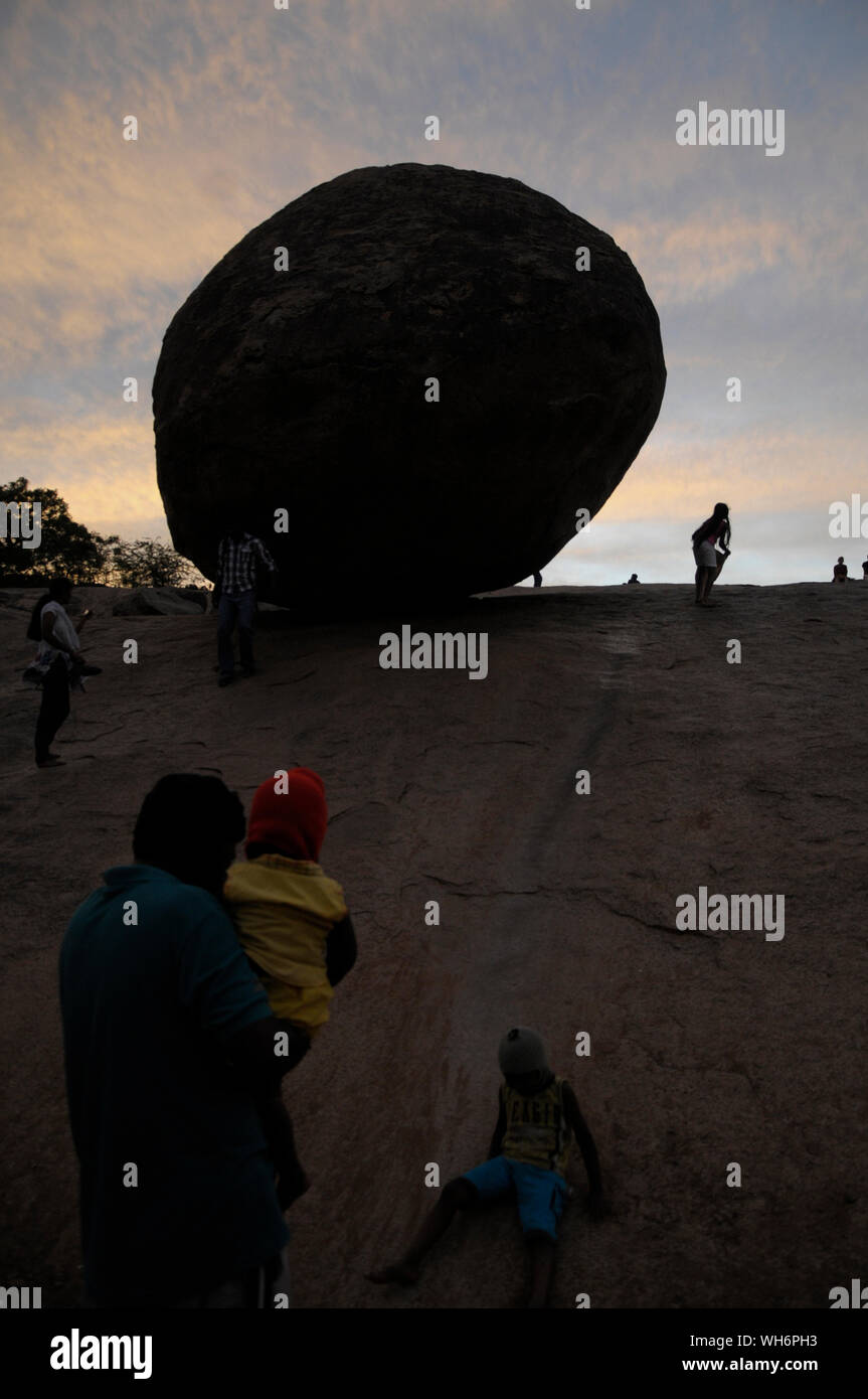 Tourists on a steep rock slope in the historic town of Mahabalipuram Tamil Nadu India where the massive round boulder known as “Krishna’s Butter Ball” Stock Photo