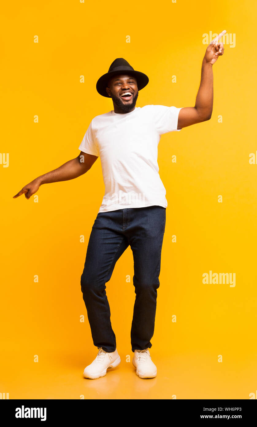 Cheerful black man dancing and pointing index fingers aside Stock Photo