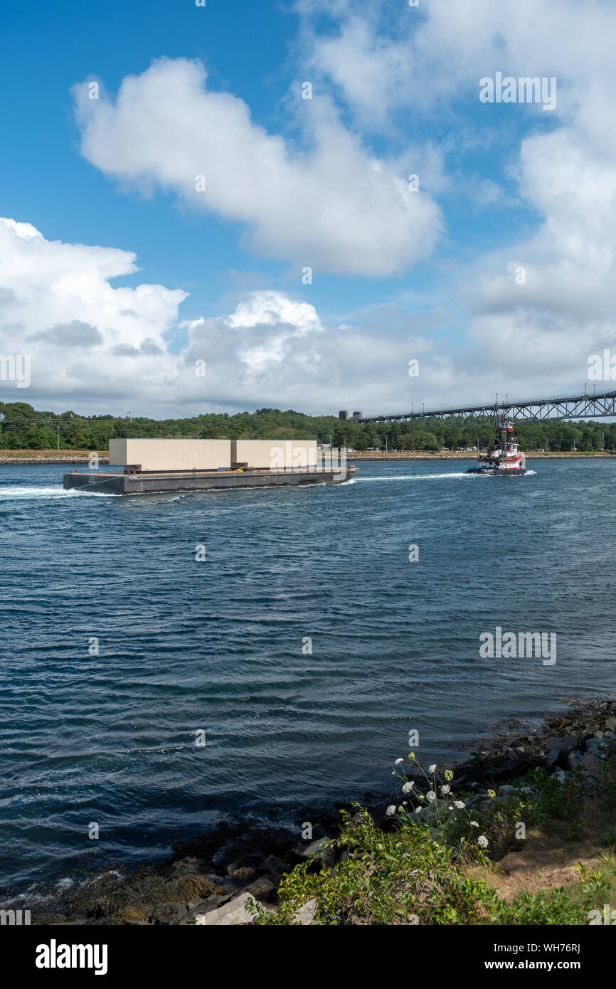 Tugboat towing a barge loaded with 2 metal containers in the Cape Cod Canal, Massachusetts USA Stock Photo