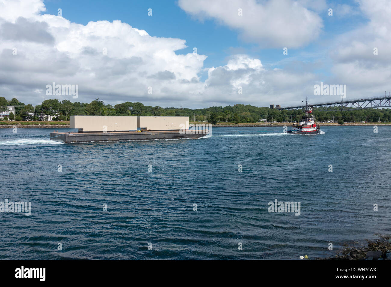 Tugboat towing a barge with metal containers in the Cape Cod Canal in Bourne, Massachusetts USA during the summer Stock Photo
