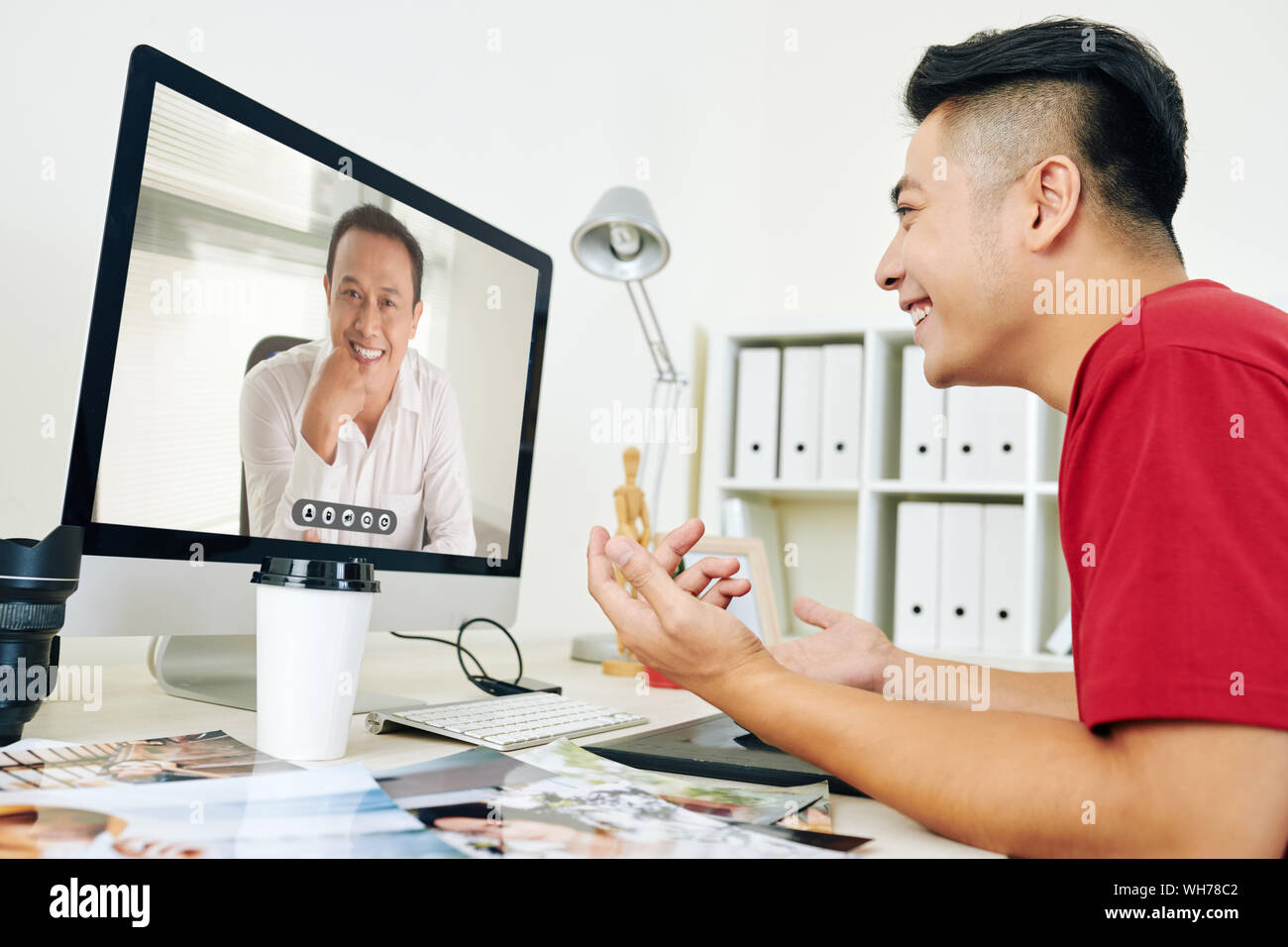 Smiling creative young man video calling his coworker or boss to ...
