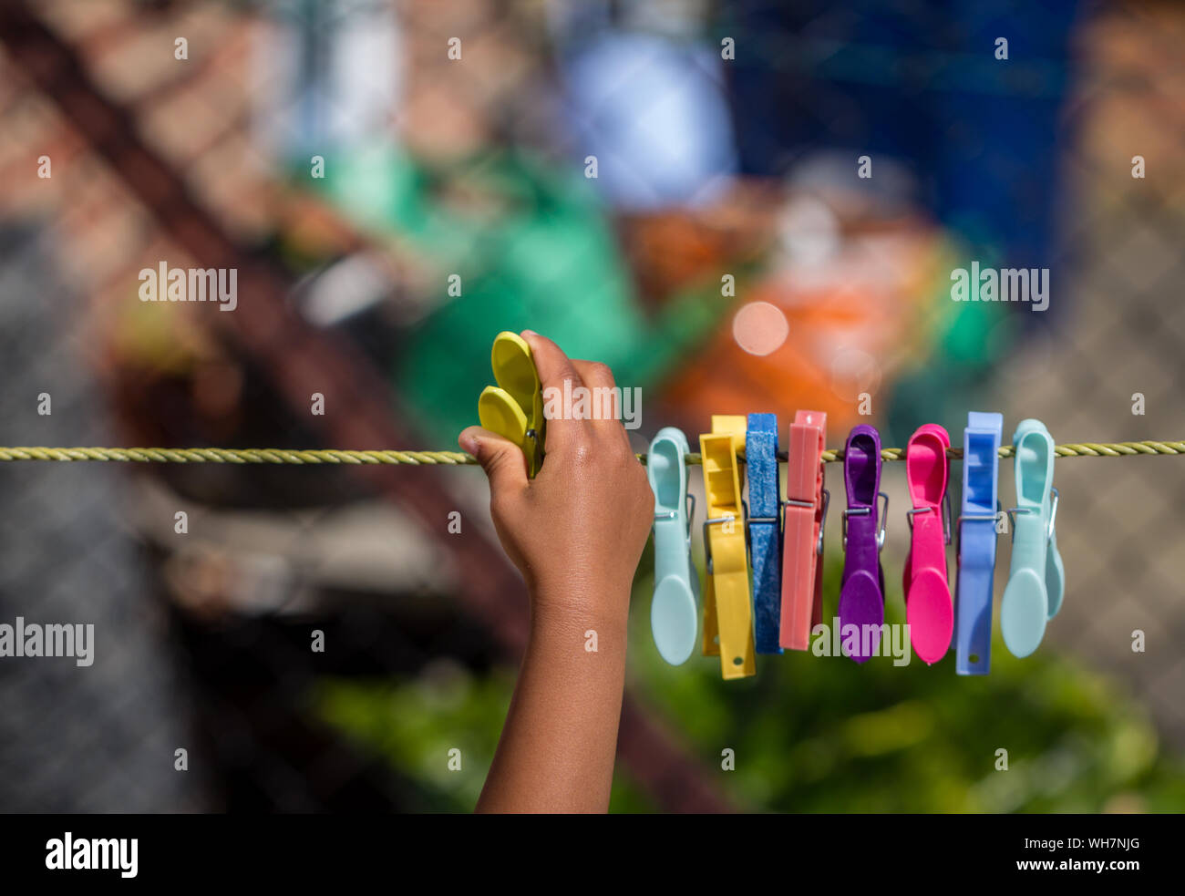 Cropped Image Of Hand Pinning Clothespin On Clothesline Stock Photo