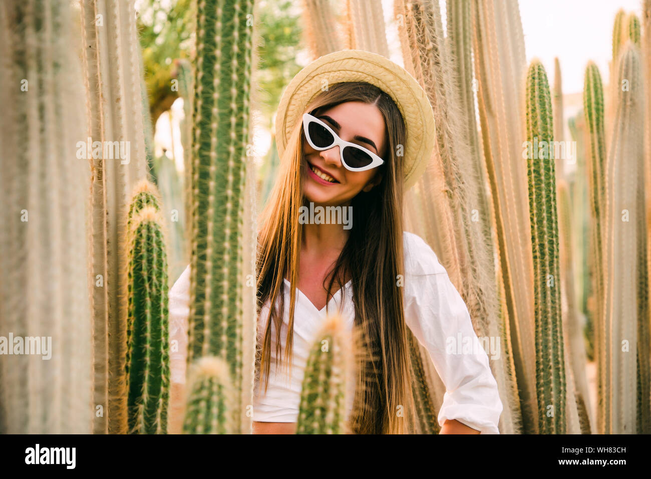 Hippie woman in long pink skirt walking near big cactuses Stock Photo