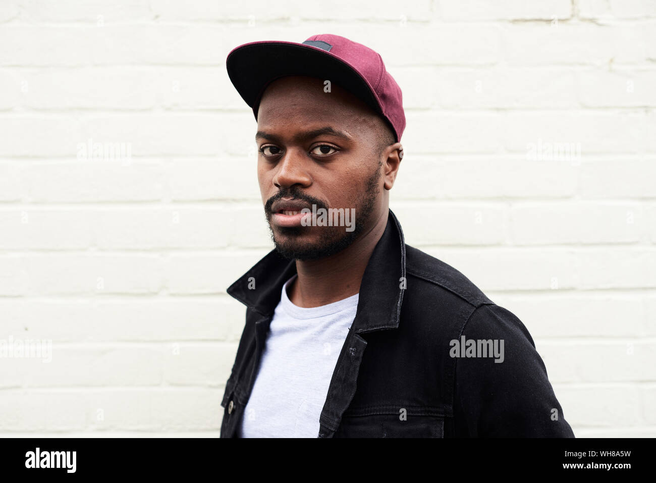 Portrait of mid adult man wearing denim jacket and basecap Stock Photo