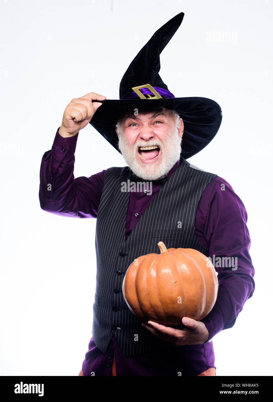 happy halloween. evil wizard hold orange pumpkin. Stargazer in holiday costume. Traditional food. bearded man ready for halloween party. mature man magician in witch hat. halloween decoration. Stock Photo