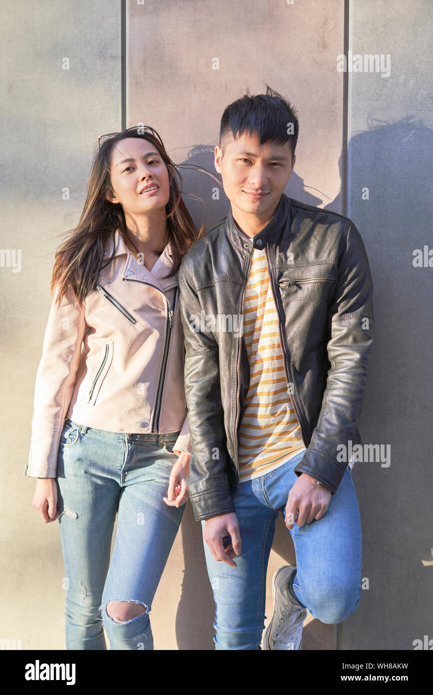 Portrait of couple wearing leather jackets leaning against wall Stock Photo