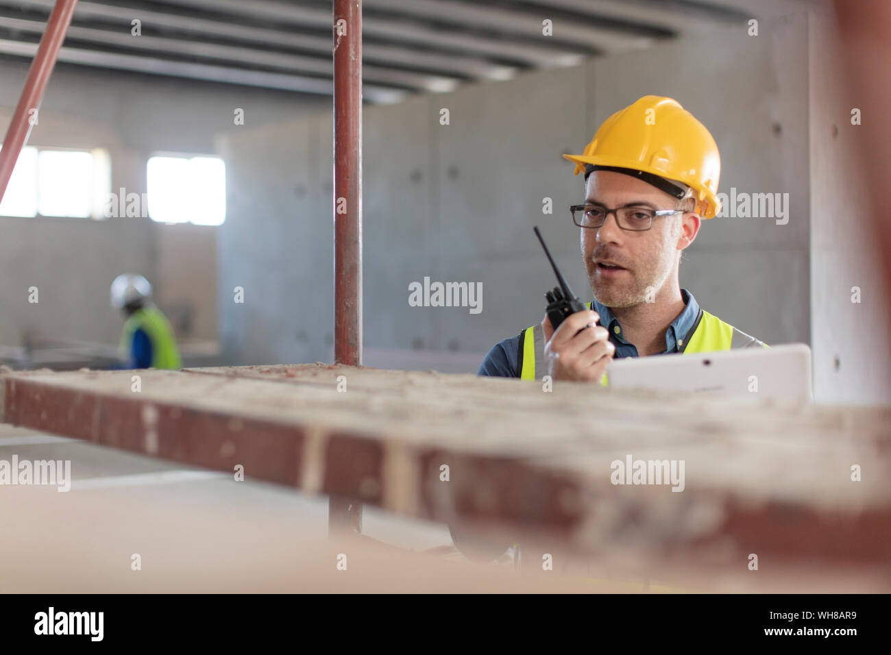Architect using walkie talkie and laptop at construction site Stock Photo
