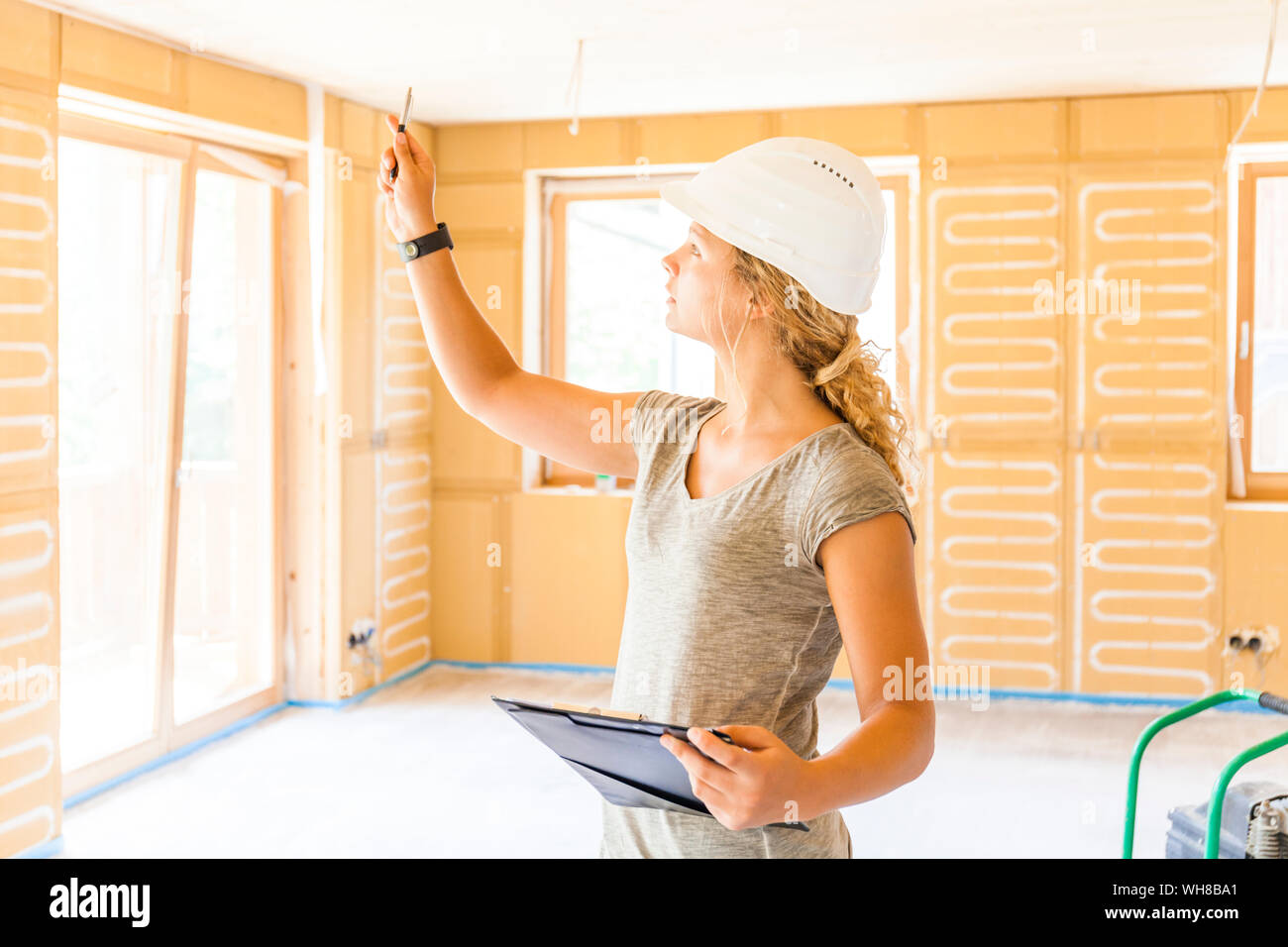 Young woman checking the construction of a new wooden house Stock Photo