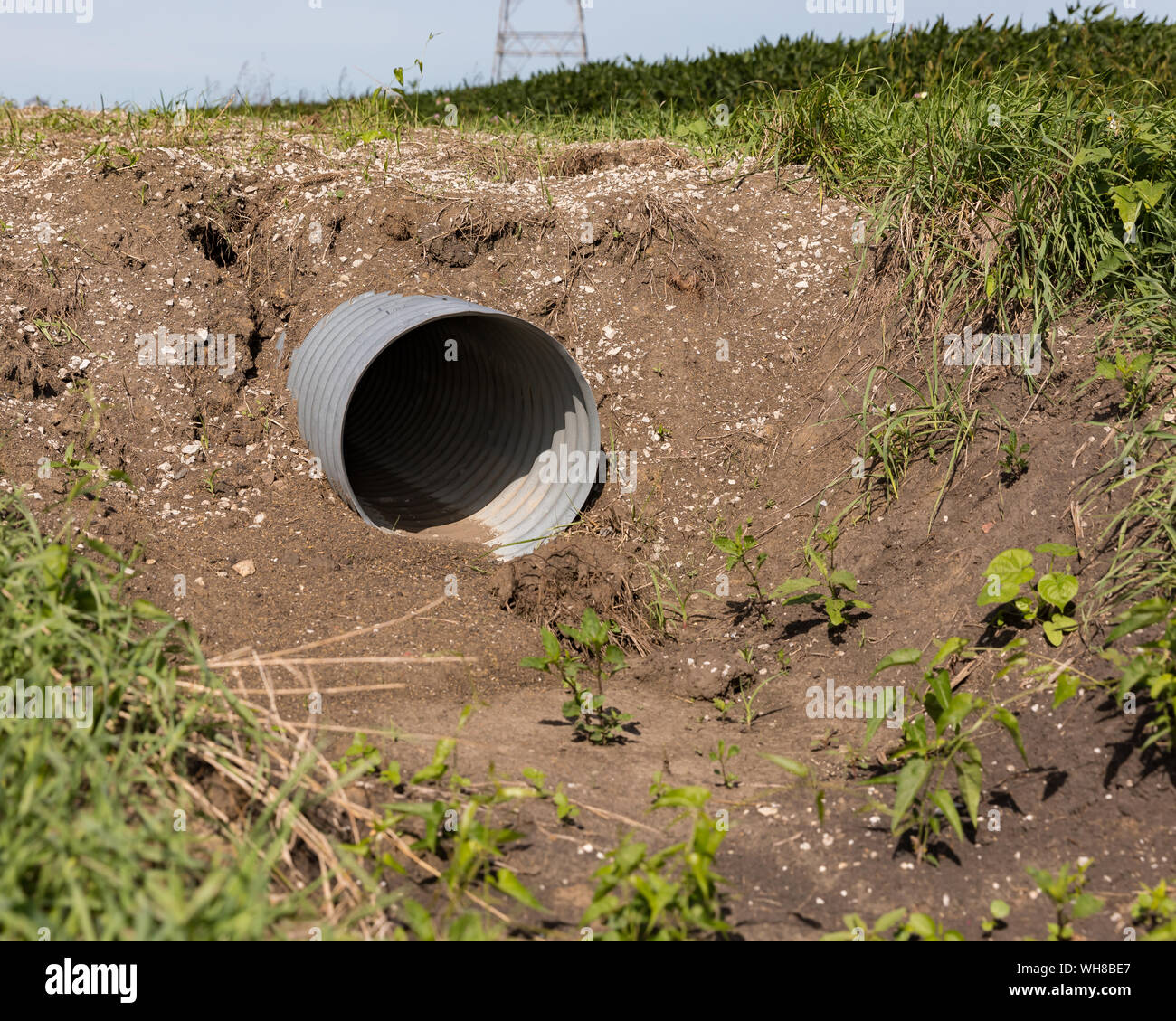 New corrugated metal drainage culvert pipe installed in ditch along road for farm field access Stock Photo