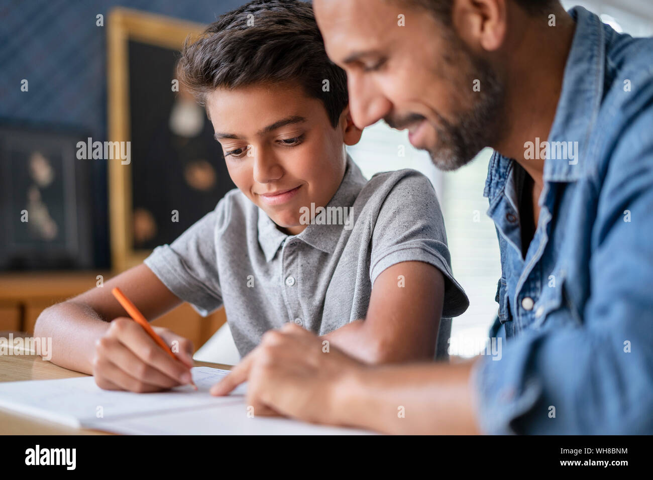 Smiling father helping son doing homework Stock Photo