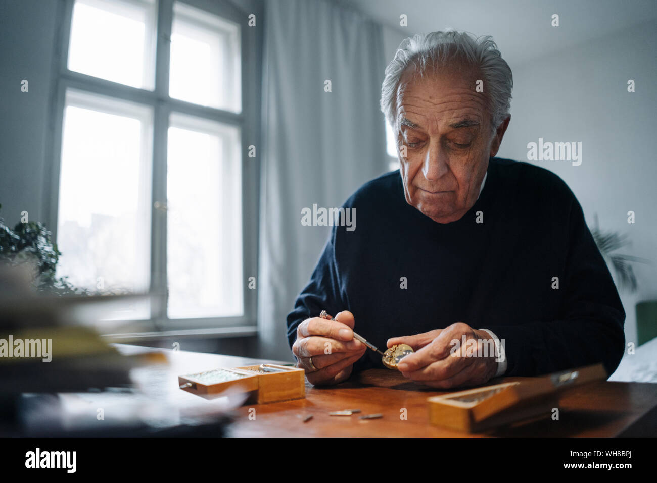 Senior man repairing a watch at home Stock Photo