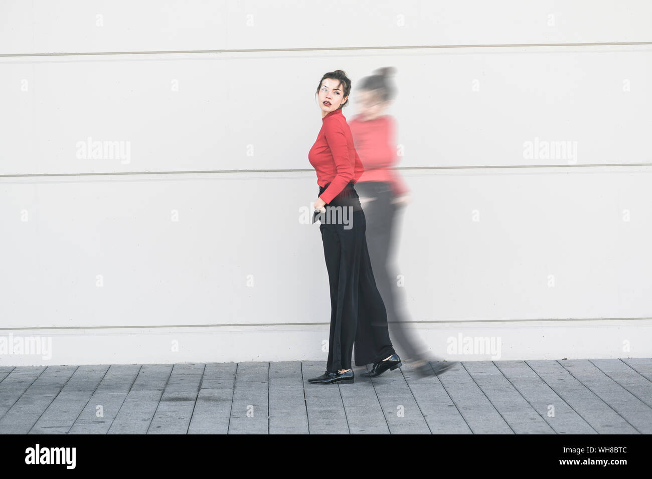 Digital composite of young woman moving in front of a wall Stock Photo