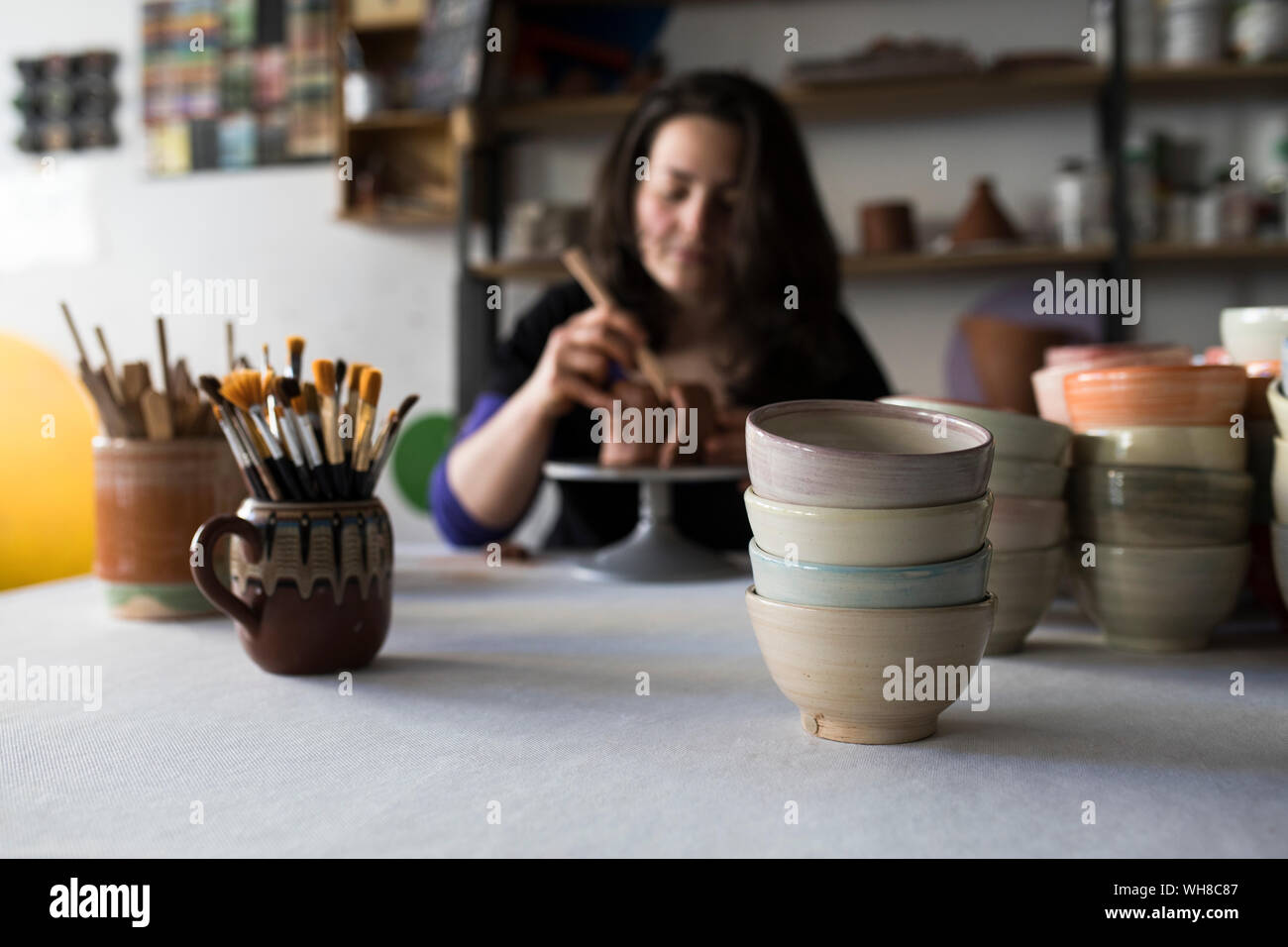 Potter shaping clay in her workshop, focus on foreground Stock Photo