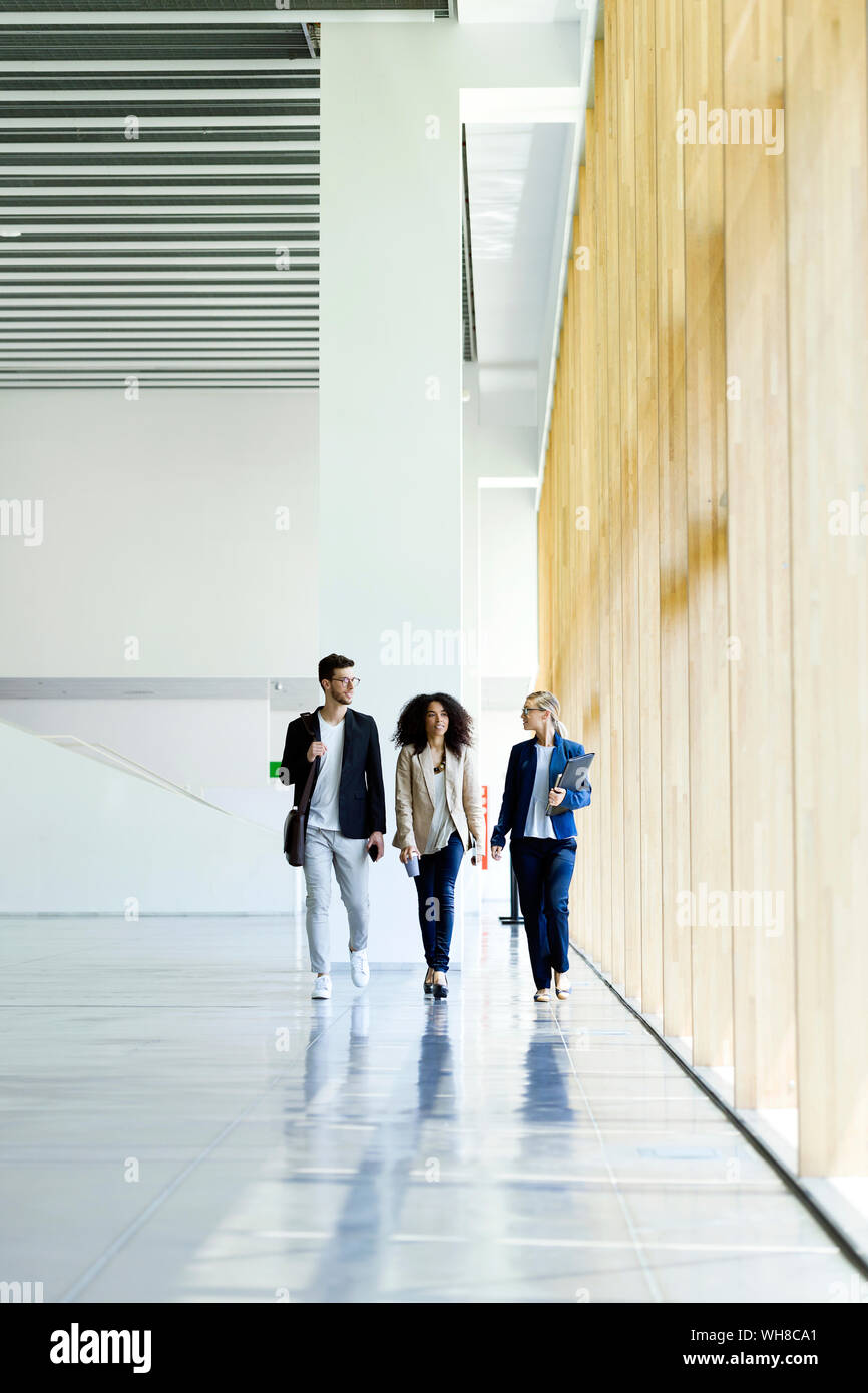 Young business people walking and talking in a hallway Stock Photo