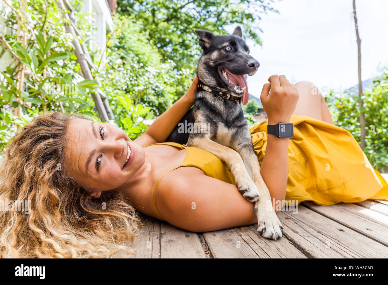 Husky shepherd mongrel dog and his mistress lying on wooden board Stock Photo