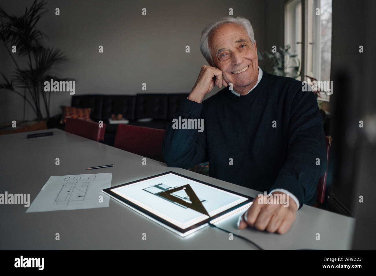 Smiling senior man using tablet with architectural plan Stock Photo