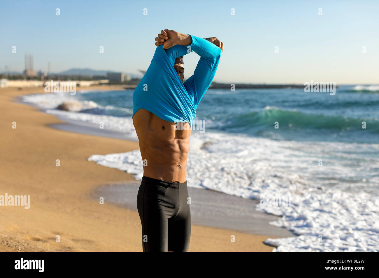Man taking off his shirt during a workout on the beach Stock Photo