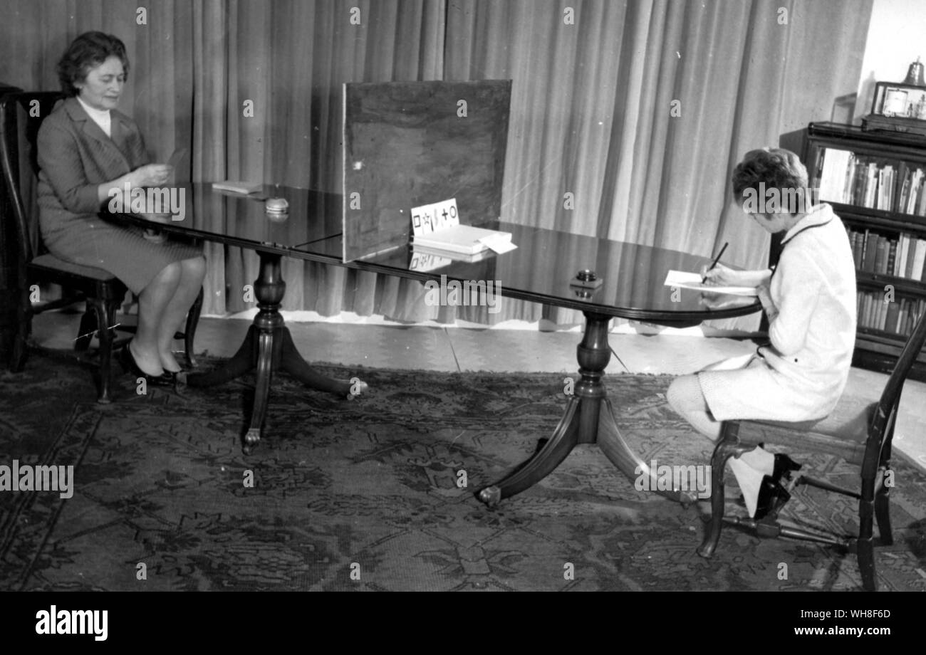 An ESP experiment in progess. The five cards used are shown in the centre of the table. The woman on the left must try and sense which of the cards the controller picks out at any given moment. Stock Photo