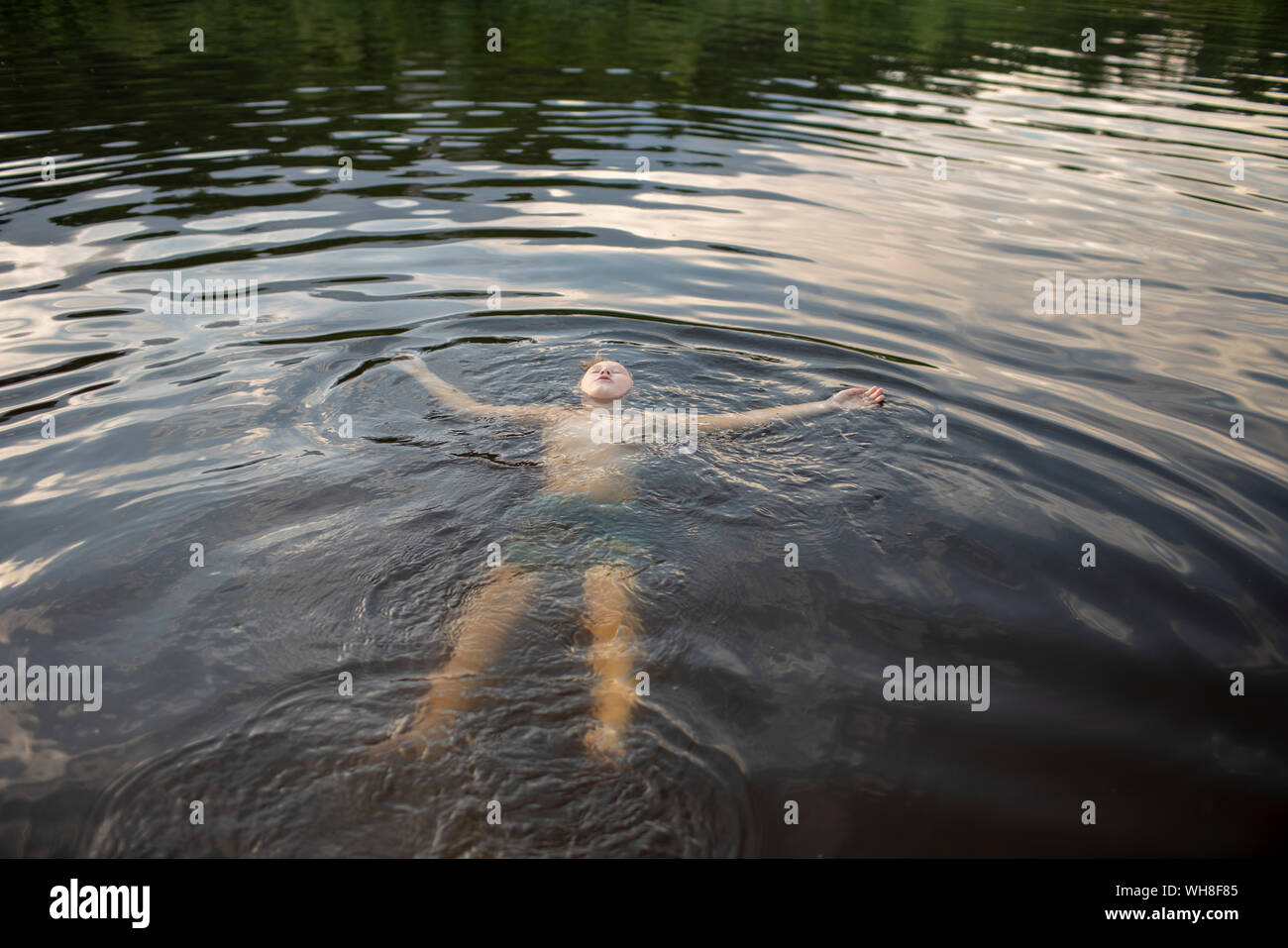 Boy floating in a lake in the evening Stock Photo