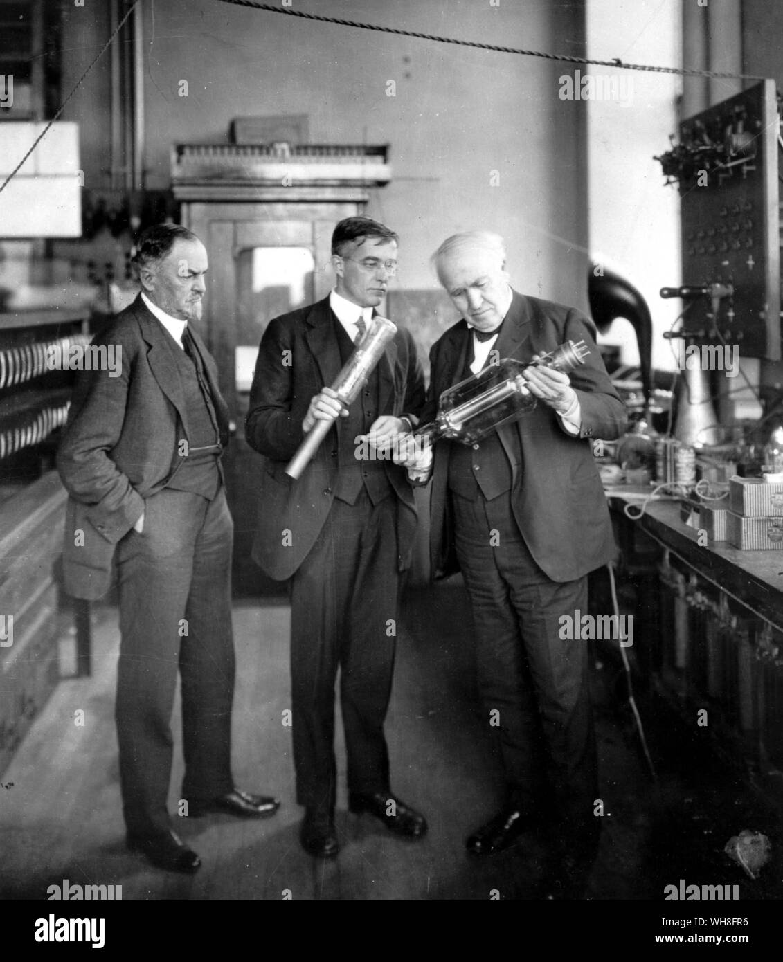 George Morrison on the left, manager of the General Electric Works, and Thomas Alva Edison with Dr. Irving Langmuir, examining vacuum tube in research laboratory 1922.. . . . . . Stock Photo