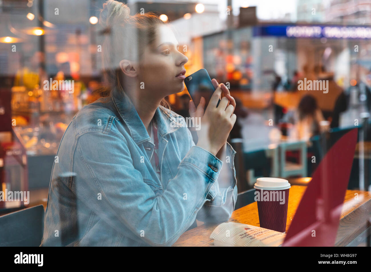 Young woman with smartphone in a cafe Stock Photo