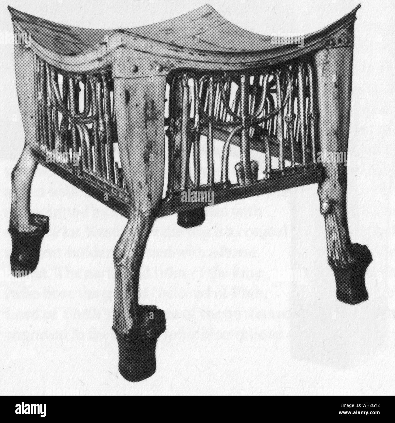 Ornate stool found in Tutankhamun's tomb. The Treasures of Tutankhamen, The Exhibition Catalogue by I E S Edwards, page 101.. The feet, in form of a member of the cat family's paws, are of wood painted white. Between them can be observed a gilded motif of the Union of the Two Countries in openwork wood, taking the form of lilies and papyruses entwined around the hieroglyphic sign signifying union. A cushion must have been placed on the curved seat. Stock Photo