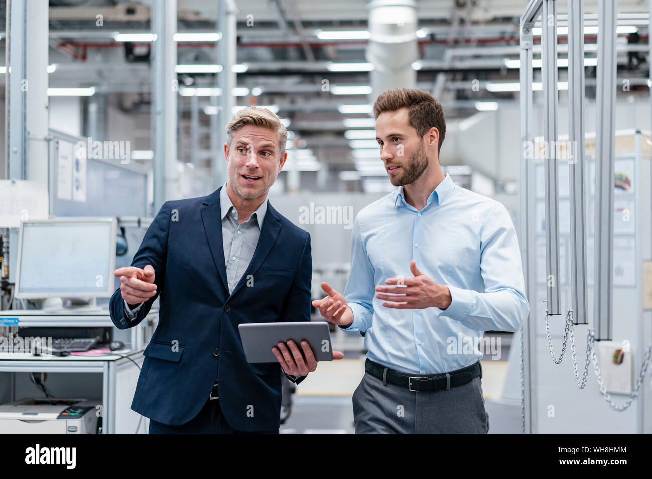 Two businessmen with tablet talking in a modern factory Stock Photo - Alamy