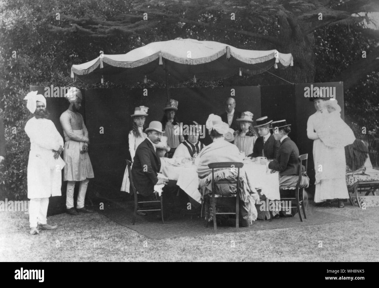 Royal Group at Osborne August 1887 left to right Muhammed Buksh. Abdul Karim (Indian Attendants) Princess Manit of Edinburgh, Victoria Beatrice, Princess Henry of Battenburg (back view) Stephen Mashin (page) Princess Alexandra of Edinburgh, Princess Alix of Hesse, Princess Irene of Hesse, nurse holding Prince Alexander of Battenberg Stock Photo