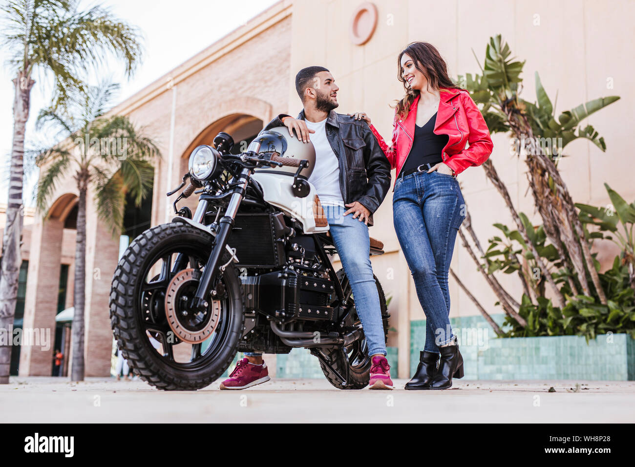 Beautiful stylish young couple posing with motorbike in garage Stock Photo  - Alamy