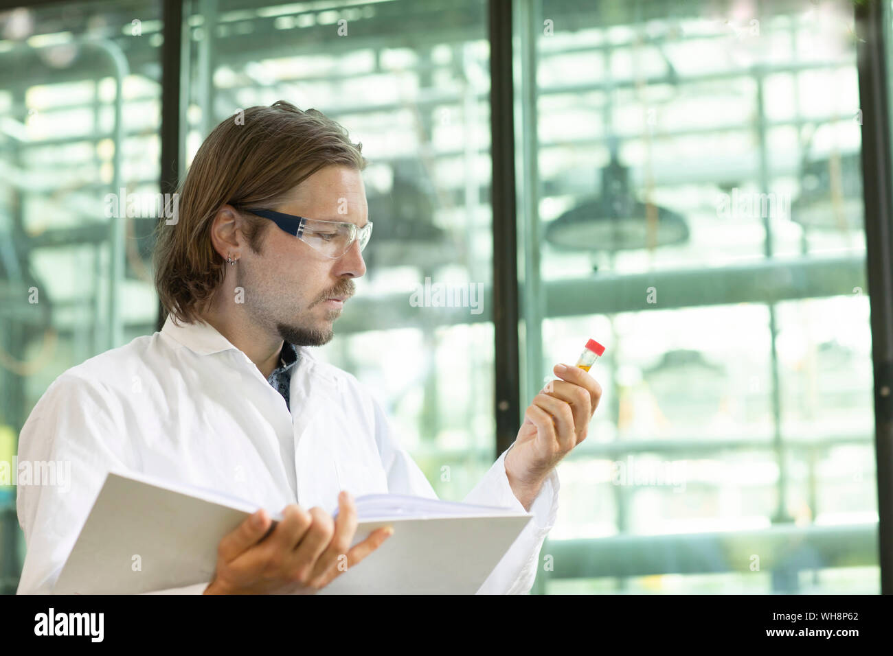 Researcher in a laboratory coat examining plants in a greenhouse Stock Photo