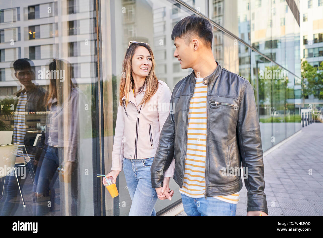 Couple wearing leather jackets walking hand in hand in the city Stock Photo