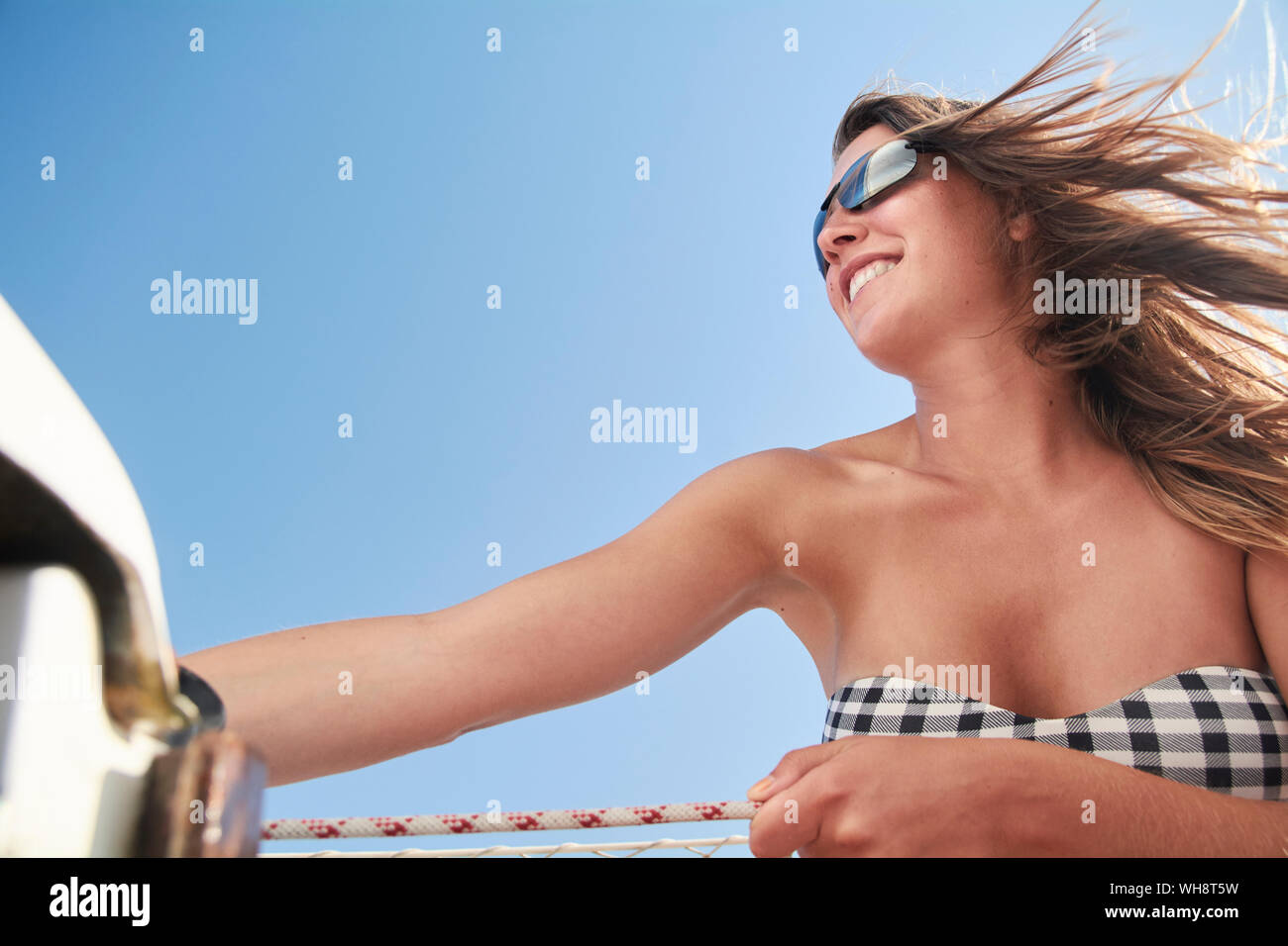 Happy woman on sailing boat against blue sky Stock Photo