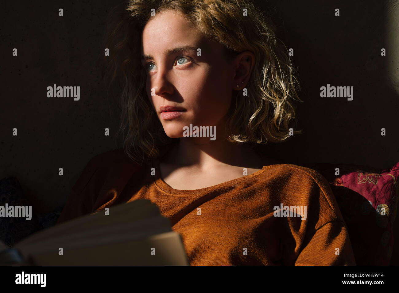 Portrait of pensive student with book looking at distance Stock Photo