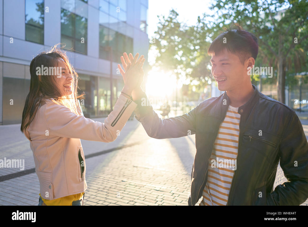 Smiling couple high fiving at sunset Stock Photo
