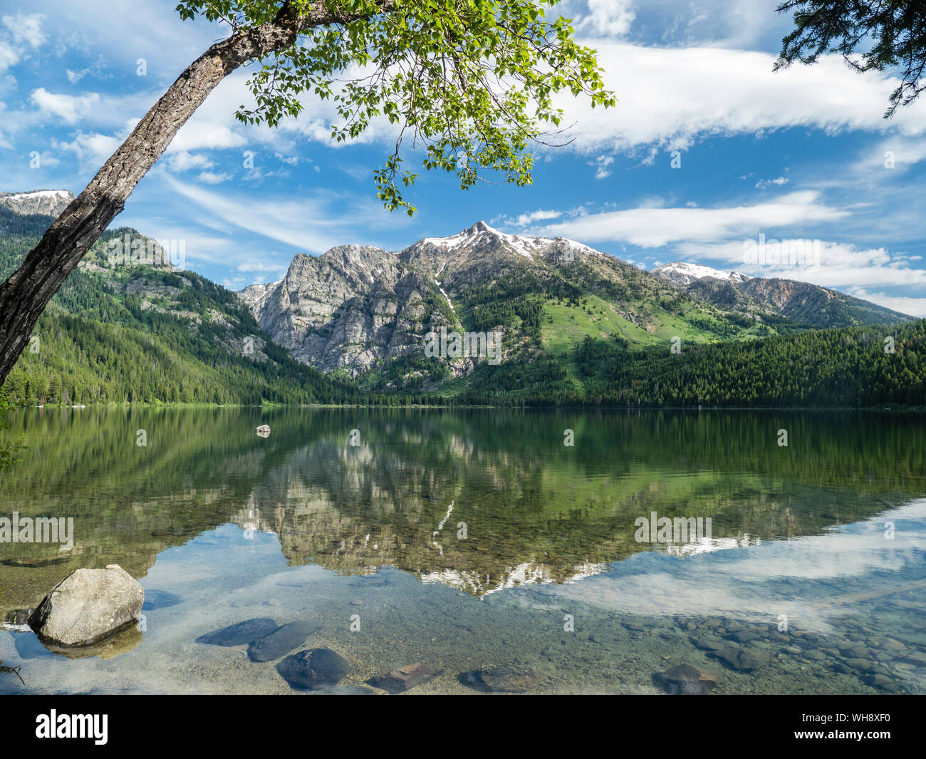 Snow-capped mountains reflected in the calm waters of Phelps Lake, Grand Teton National Park, Wyoming, United States of America, North America Stock Photo