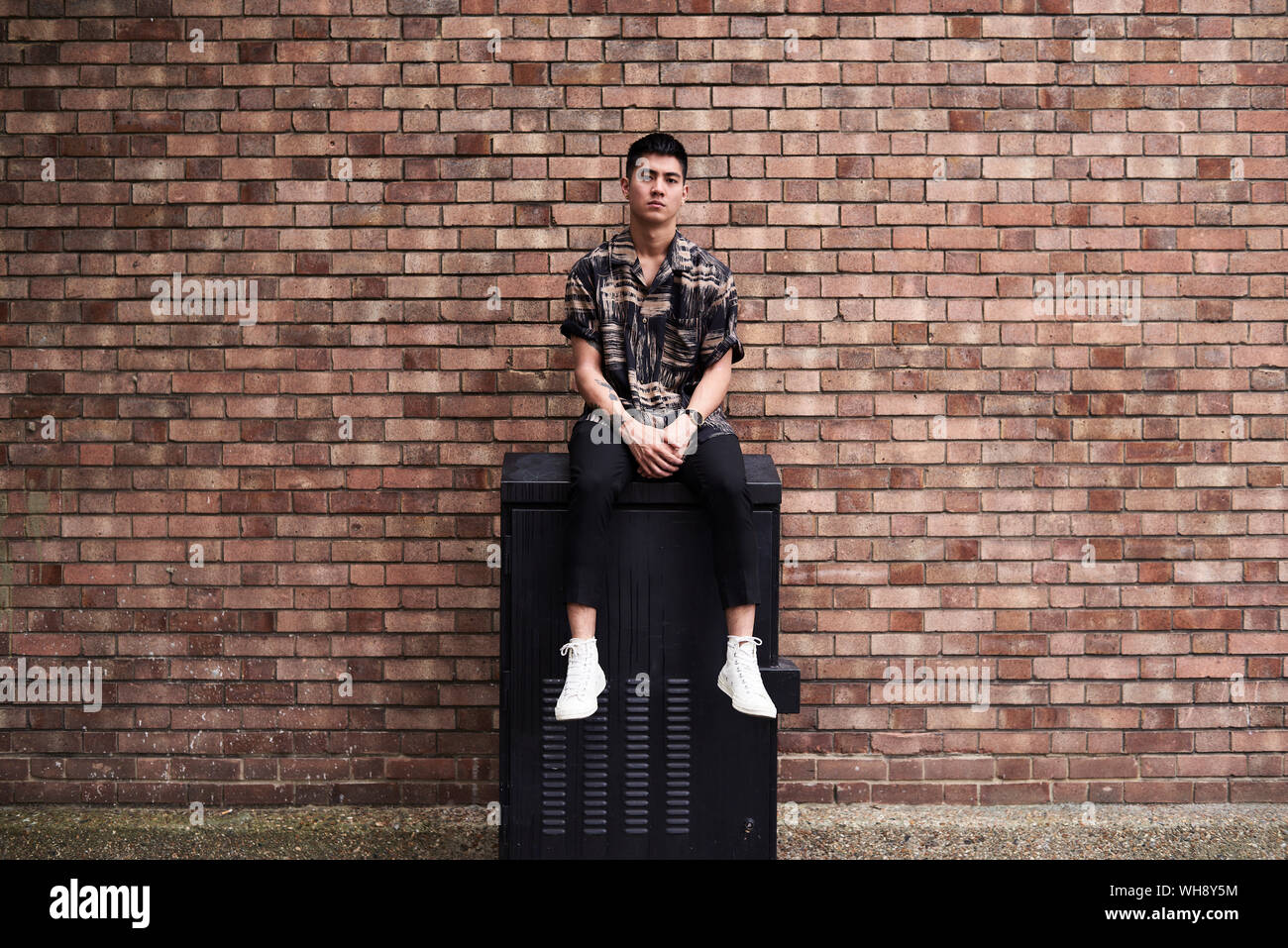 Portrait of young man in front of brick wall Stock Photo
