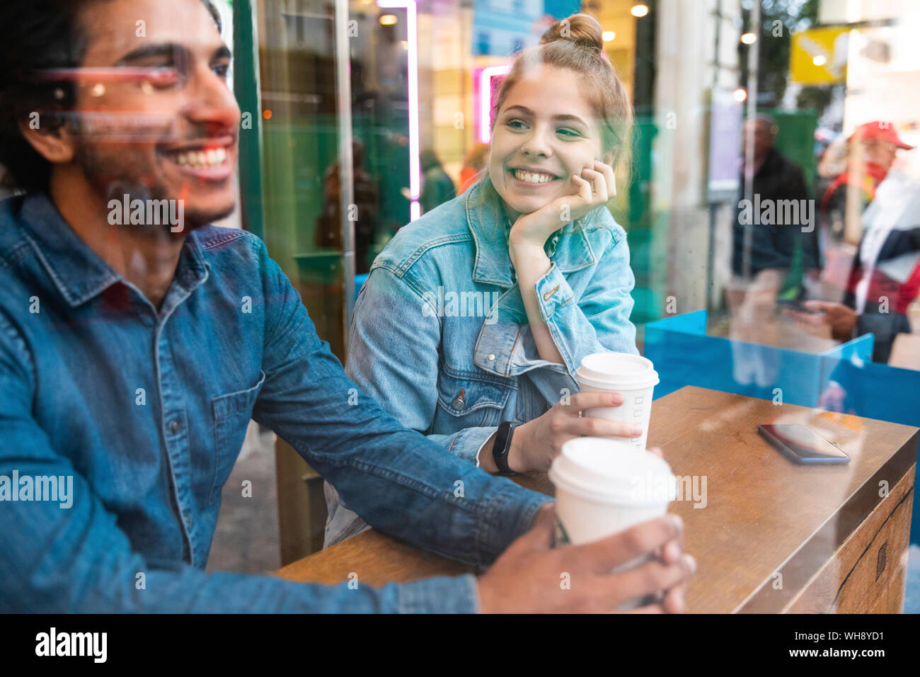 Portrait of smiling young woman in a coffee shop looking at young man Stock Photo