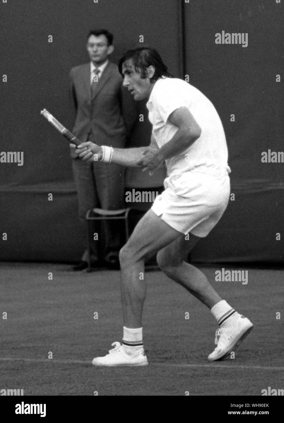 A lucky shot - Ile Nastase on an outside court at Wimbledon 1971, was playing forehand from the baseline and the head of the racket broke on impact and flew into the net. Nastase, still finishing the stroke, holds only the stem. Stock Photo