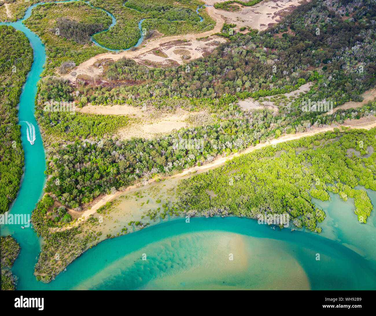 Aerial view of small boat arriving at the sea by the river, surrounded by forest in Queensland, Australia Stock Photo