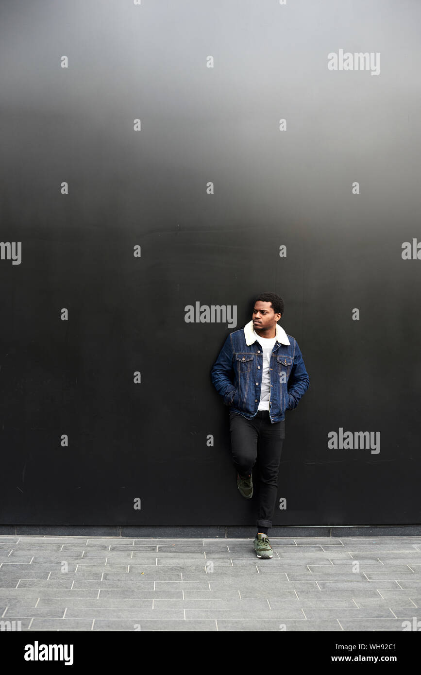 Man wearing denim jacket standing in front of dark background Stock Photo