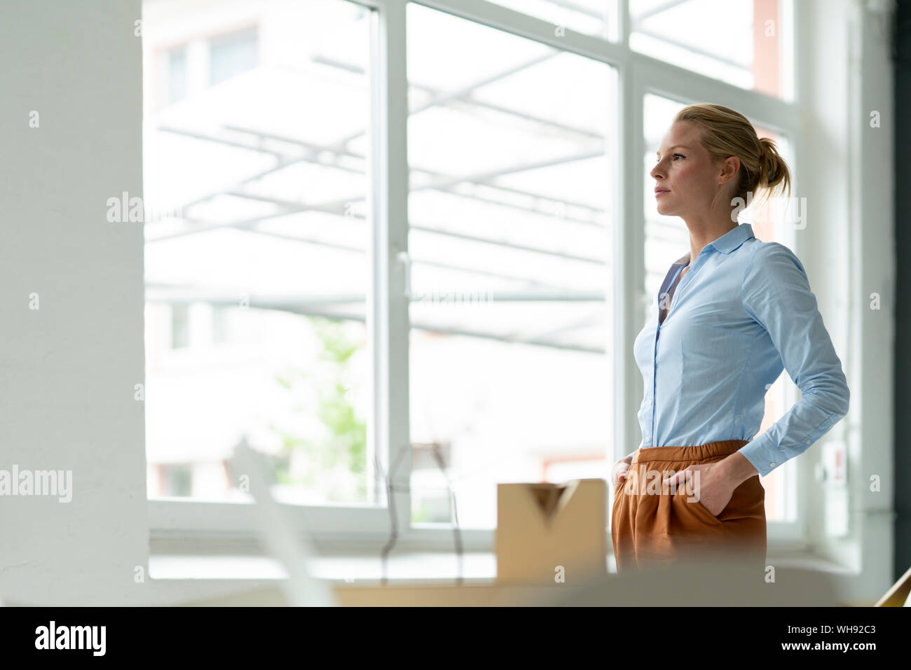 Serious young woman in office with architectural model on desk Stock Photo