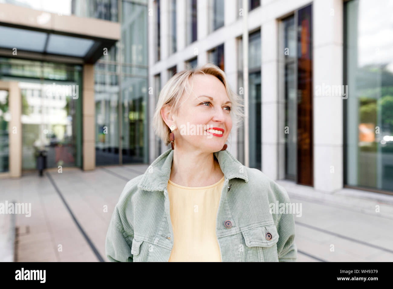 Smiling woman in the city standing outside Stock Photo