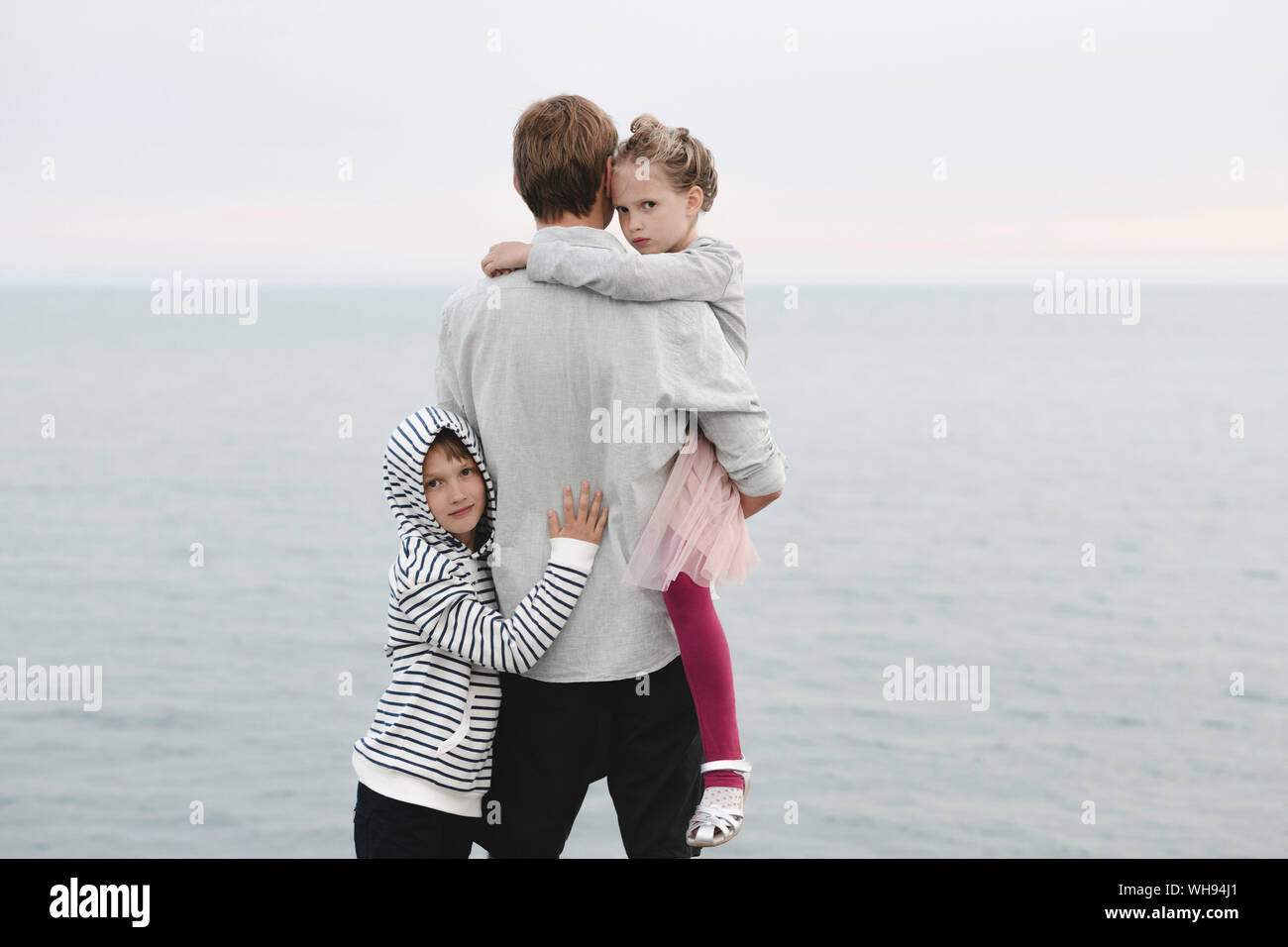 Back view of man standing in front of the sea with little daughter and son Stock Photo