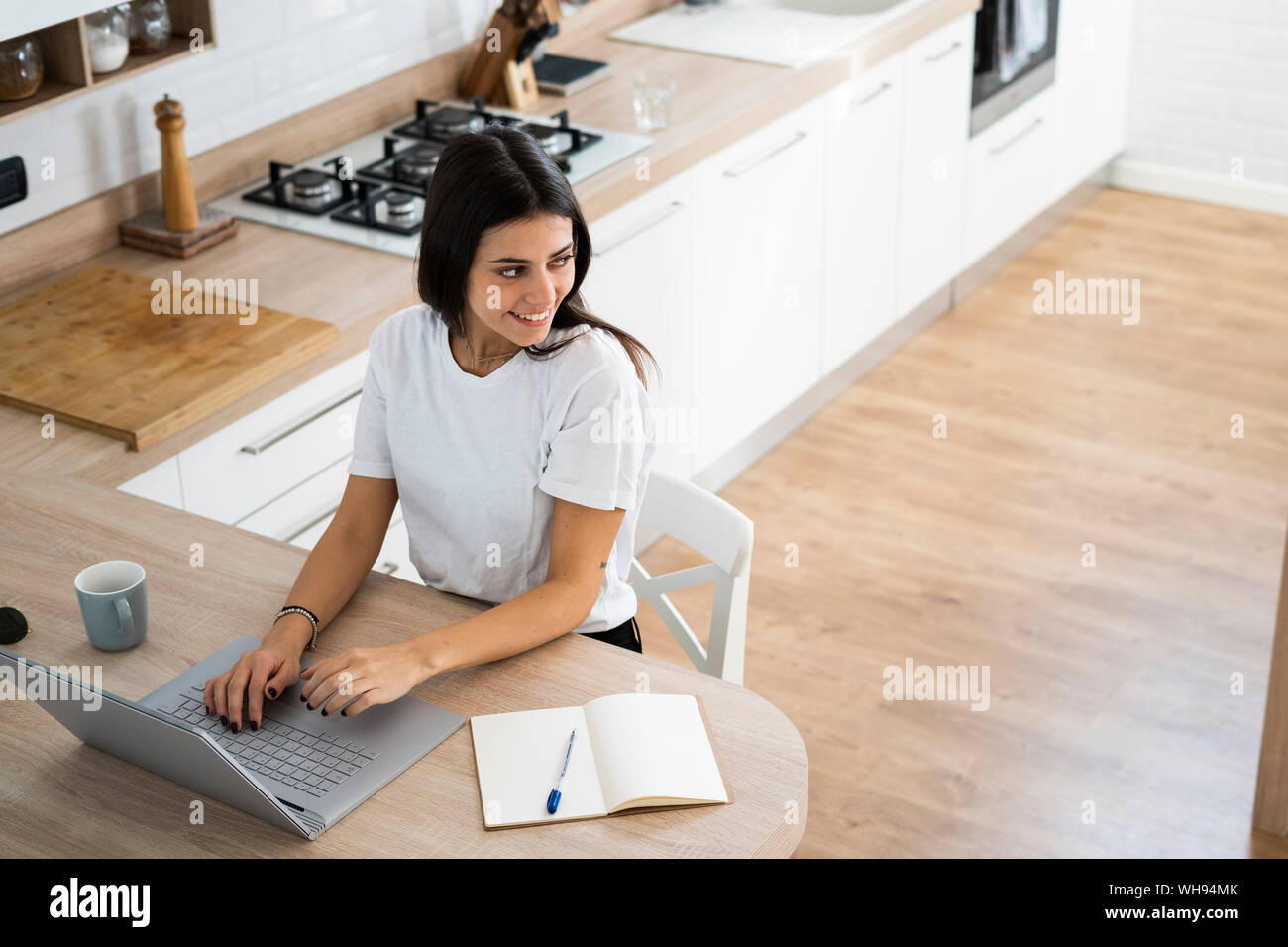 Smiling young woman using laptop at home Stock Photo
