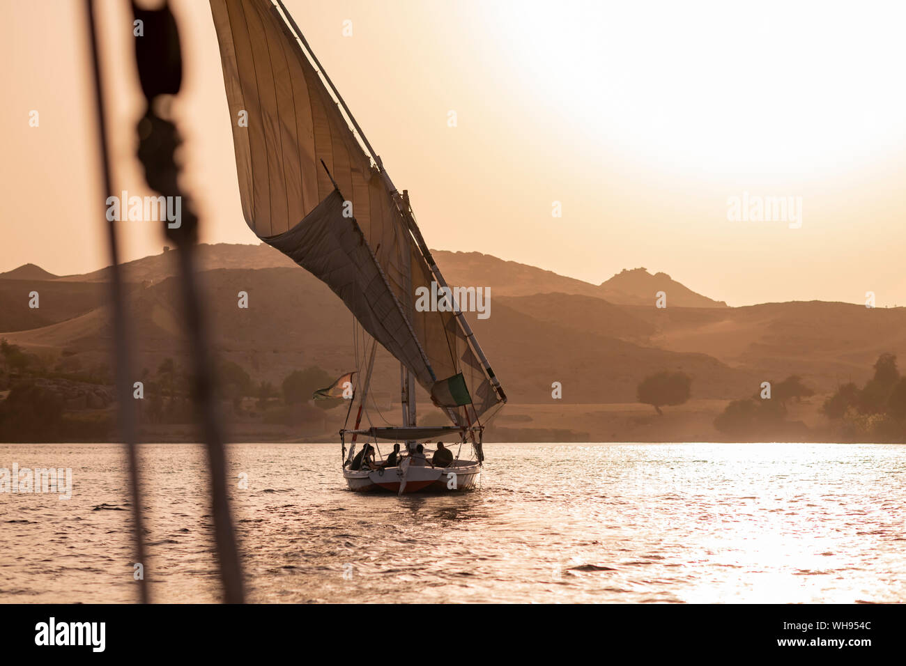 A traditional Felucca sailboat with wooden masts and cotton sails at sunset on the River Nile, Aswan, Egypt, North Africa, Africa Stock Photo