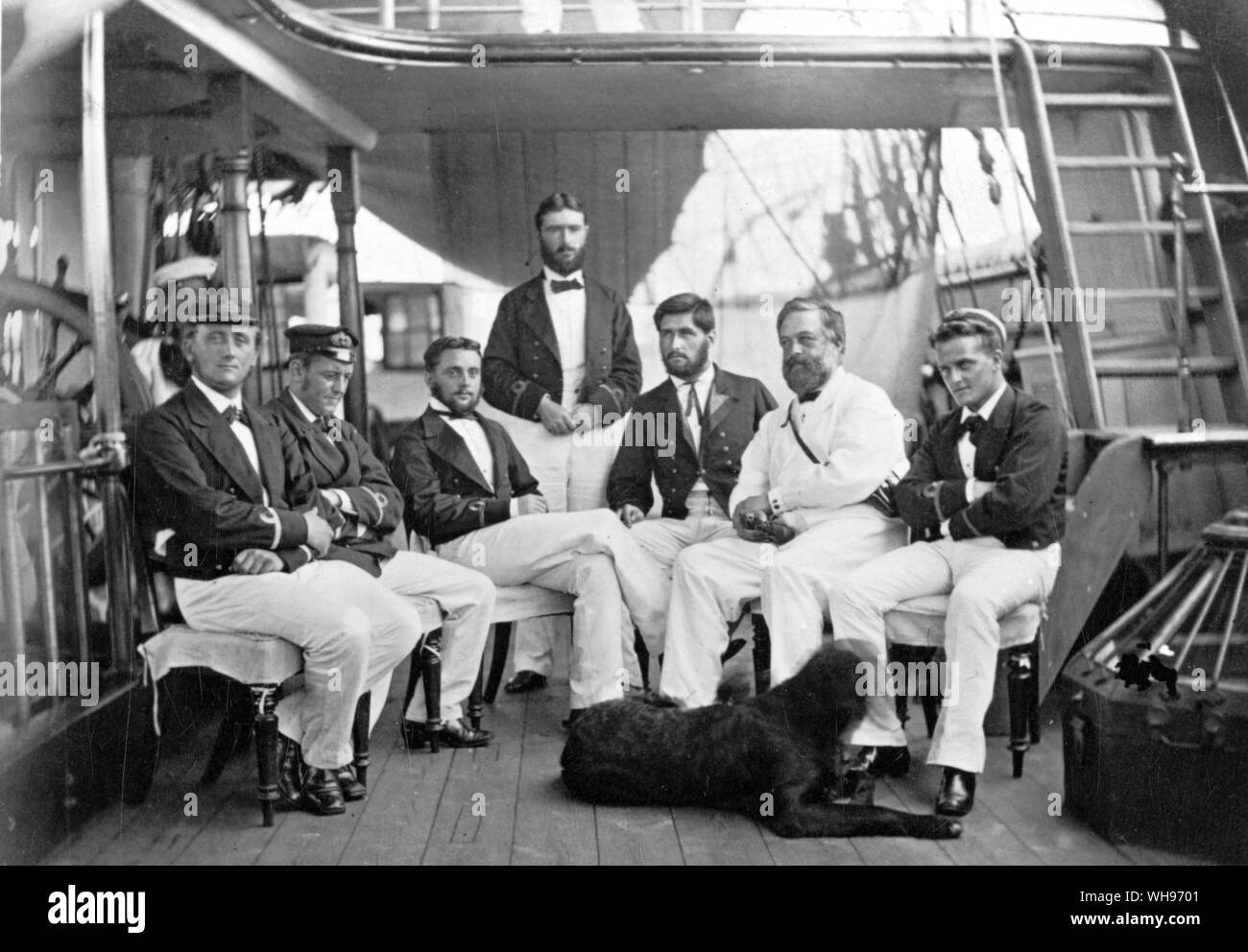 Wyville Thompson, all in white, sits among the sub-lieutenants. On his left is Lord George Campbell. on his right is Herbert Swire. All pose stiffly for the camera except for the Newfoundland dog, who never learned the meaning of a time-exposure.. Stock Photo